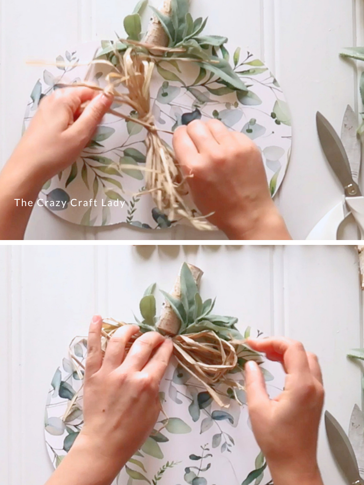 embellish pumpkin with raffia bow and hot glue
